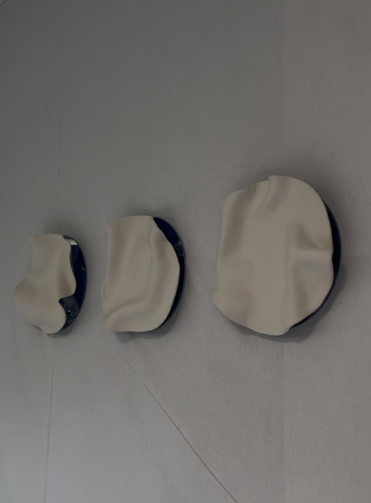 Trzy ceramiczne obiekty ścienne o falujących krawędziach